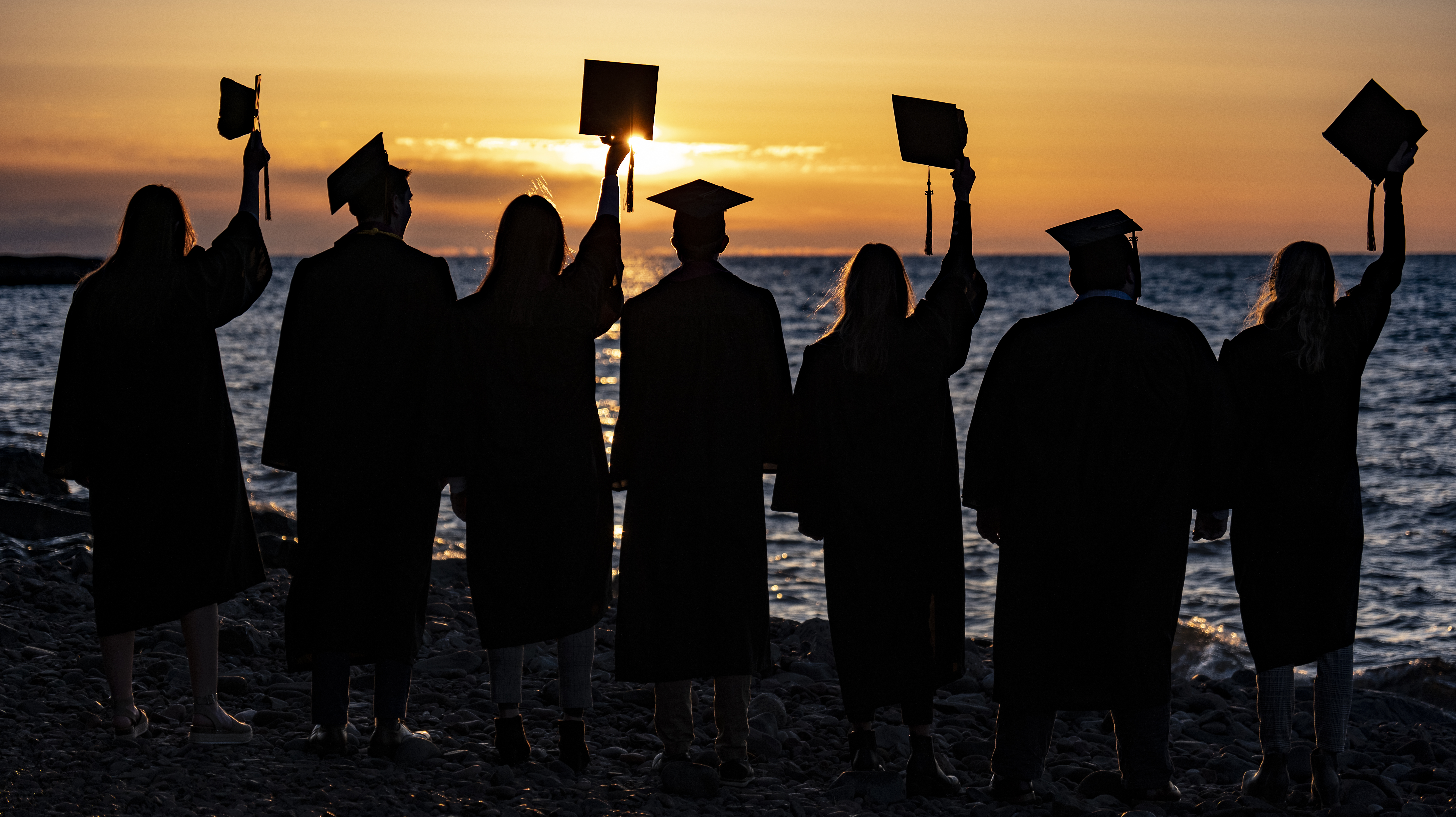Graduates standing at Lake Superior at sunrise