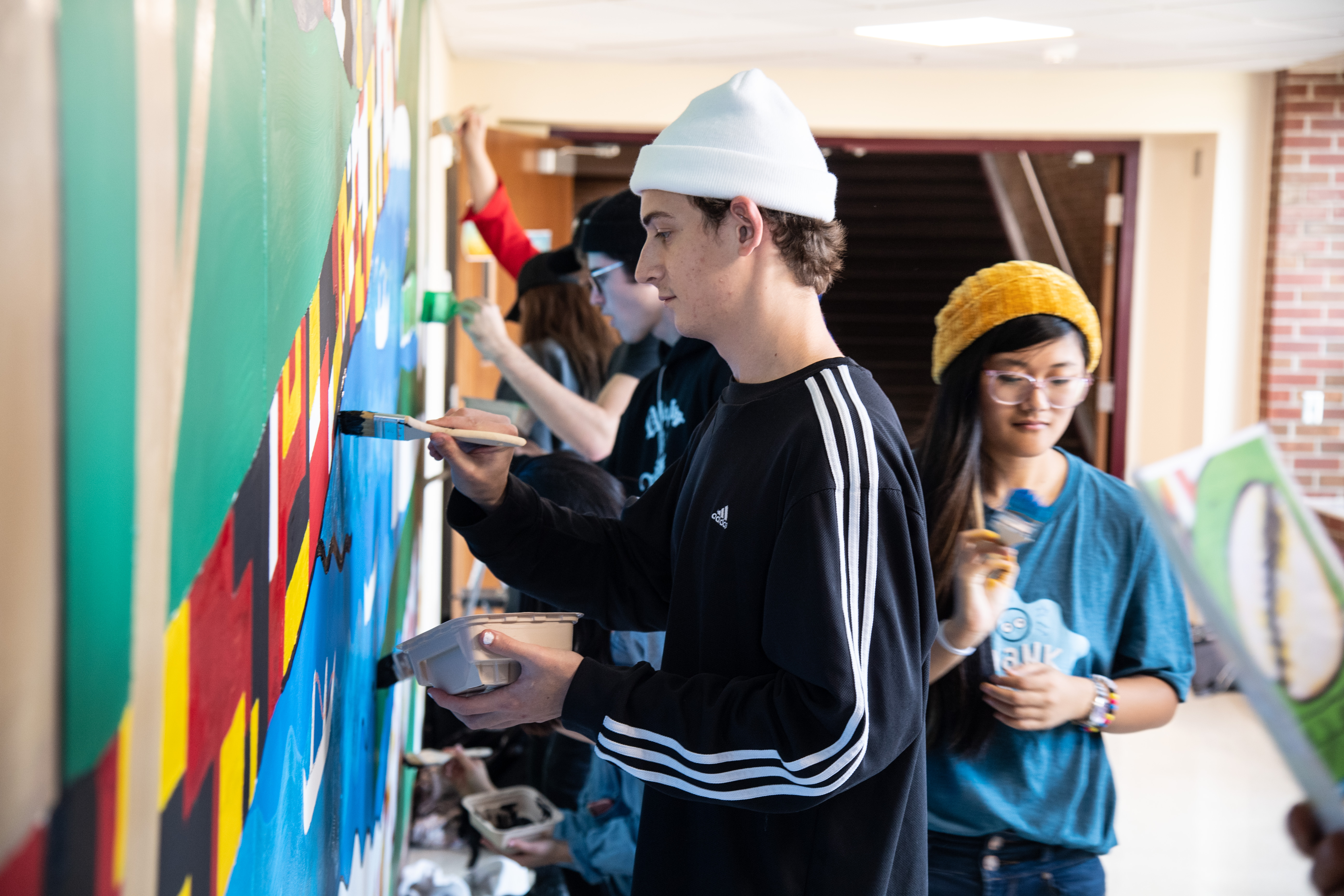 Variety of students painting a mural.